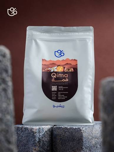 Qima premium coffee bag on stone, navy and terracotta label
